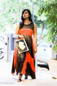 Black and orange maxi dress styled with a bold multi-stone necklace and a black and gold purse.
